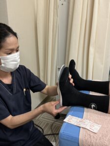 三軒茶屋の整骨院で、スタッフが足にインソールを合わせている様子